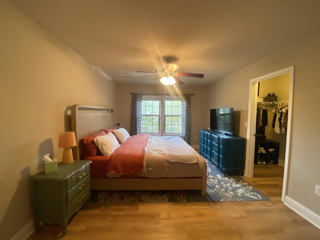 bedroom featuring ceiling fan, a closet, a spacious closet, and hardwood / wood-style flooring