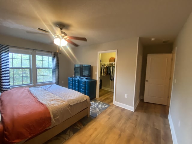 bedroom featuring light wood-type flooring, a closet, a spacious closet, and ceiling fan