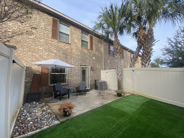 rear view of property featuring a lawn, a patio area, and central AC