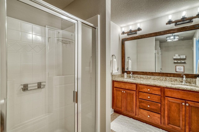 bathroom featuring vanity, a textured ceiling, and a shower with door