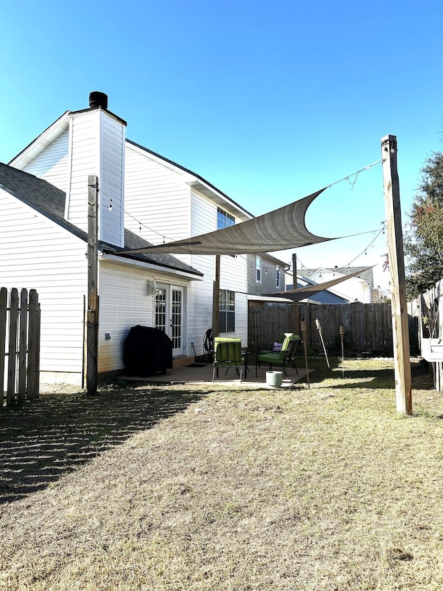 rear view of house with french doors, a patio area, and a lawn