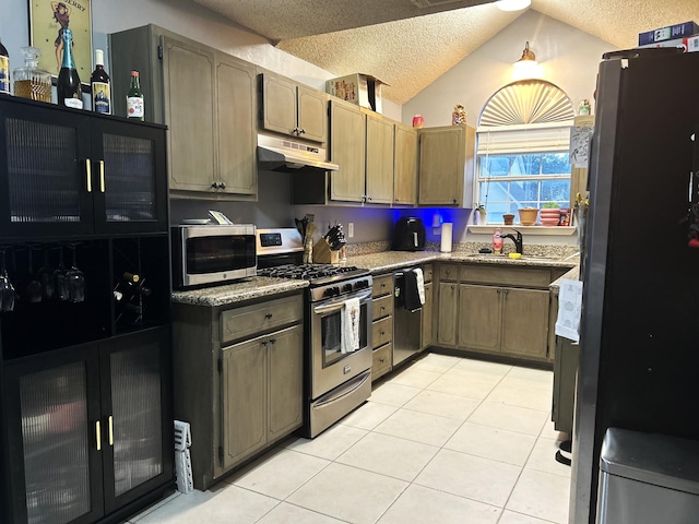 kitchen featuring lofted ceiling, sink, light tile patterned floors, a textured ceiling, and stainless steel appliances