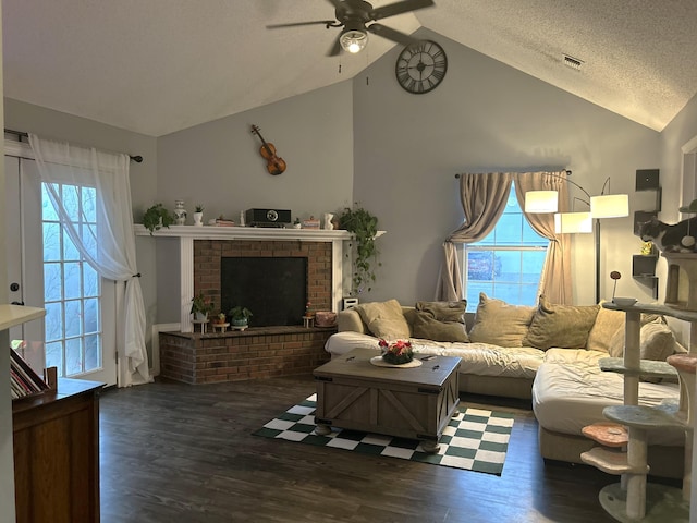 living room featuring ceiling fan, dark hardwood / wood-style flooring, a textured ceiling, and a brick fireplace