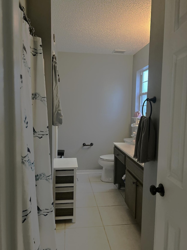 bathroom with tile patterned flooring, vanity, toilet, and a textured ceiling