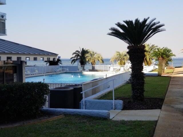 view of swimming pool featuring a water view, central AC, and a lawn