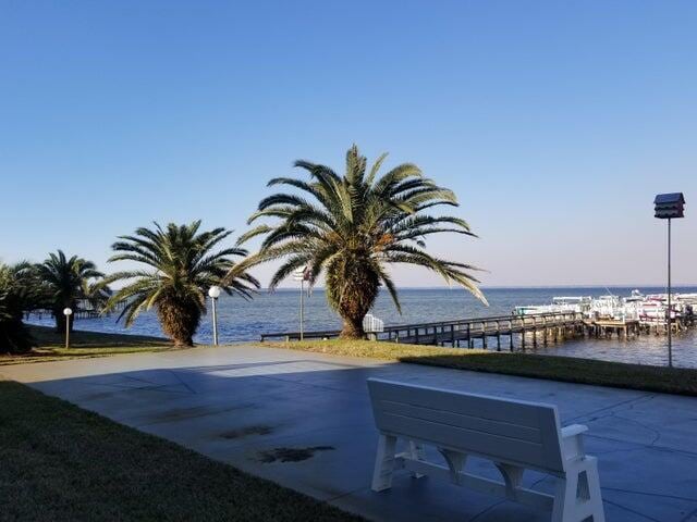 patio terrace at dusk featuring a water view and a boat dock