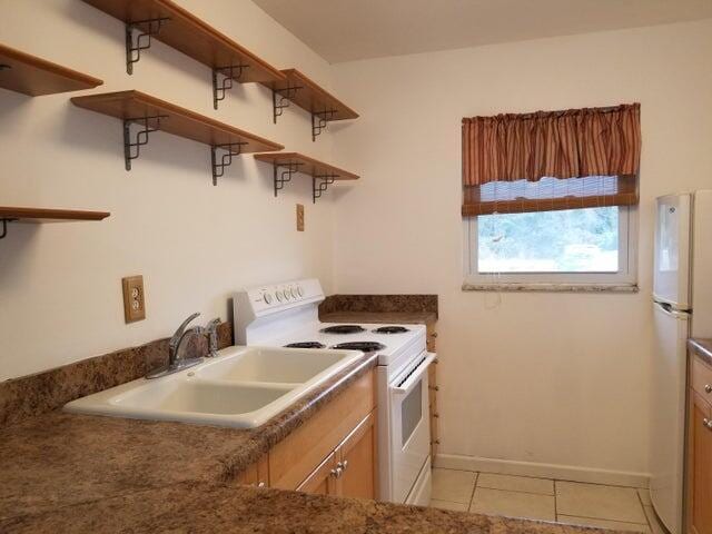 kitchen featuring white appliances, sink, and light tile patterned floors