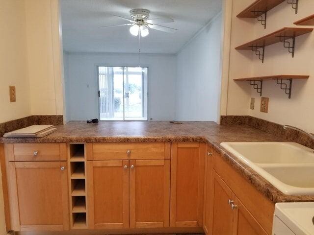 kitchen with ceiling fan, kitchen peninsula, and sink