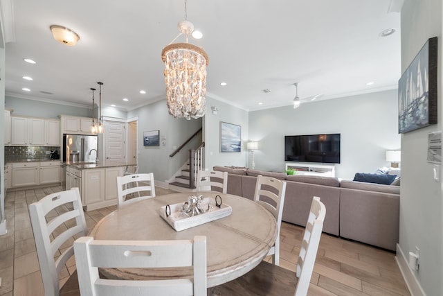 dining space featuring ceiling fan with notable chandelier, light wood-type flooring, and ornamental molding