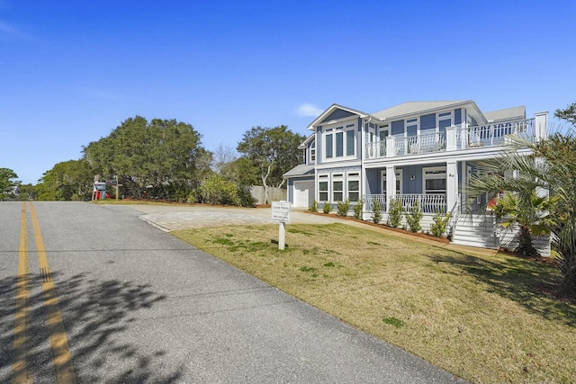 view of front of house featuring a balcony, a front yard, a porch, and a garage