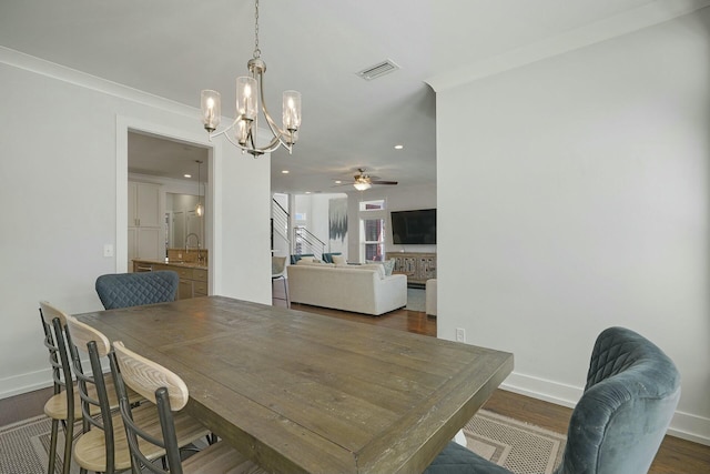 dining room with ceiling fan with notable chandelier, dark hardwood / wood-style flooring, and ornamental molding