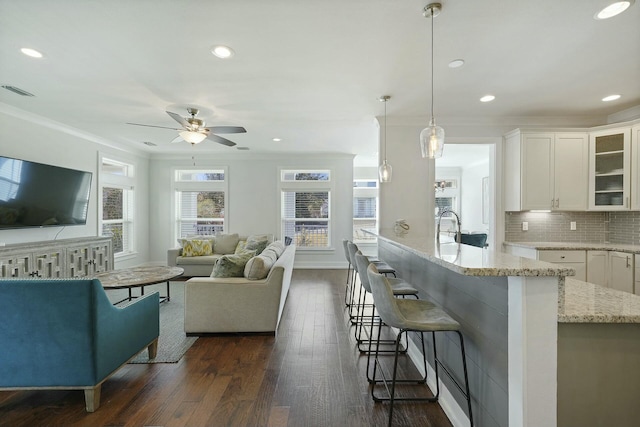 living room with ornamental molding, ceiling fan, dark wood-type flooring, and sink