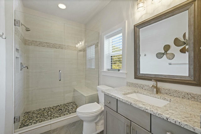 bathroom with tile patterned floors, vanity, toilet, and a shower with shower door