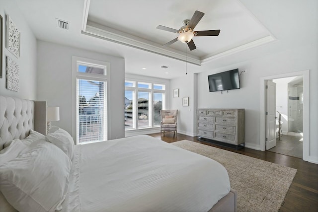 bedroom featuring ceiling fan, dark hardwood / wood-style floors, a raised ceiling, and connected bathroom