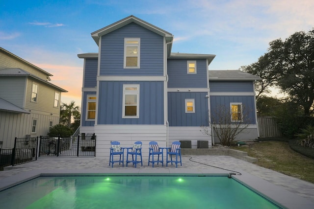 back house at dusk featuring a fenced in pool and a patio area