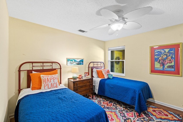 bedroom with ceiling fan, hardwood / wood-style floors, and a textured ceiling