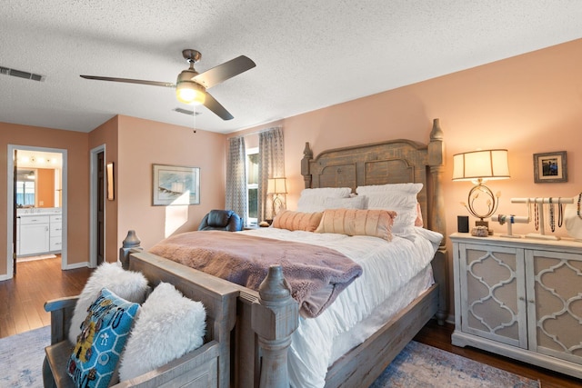 bedroom with a textured ceiling, ensuite bath, ceiling fan, and dark wood-type flooring