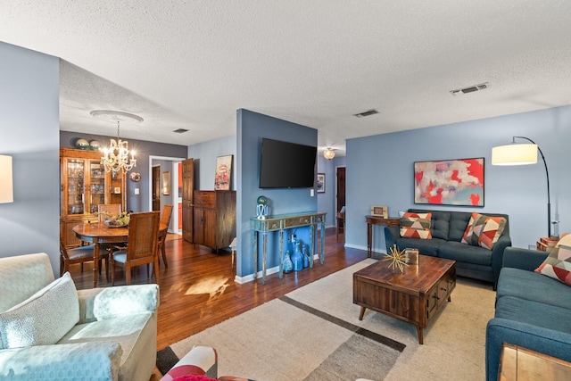 living room with a chandelier, a textured ceiling, and light hardwood / wood-style flooring