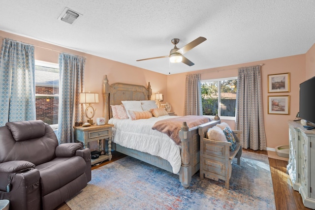 bedroom with hardwood / wood-style floors, a textured ceiling, and ceiling fan