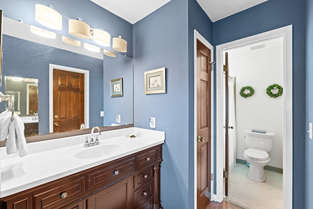 bathroom featuring vanity, a textured ceiling, and toilet