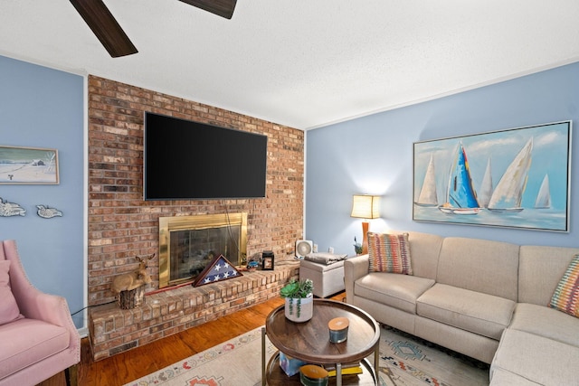 living room featuring wood-type flooring, a textured ceiling, and a brick fireplace