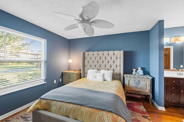 bedroom featuring multiple windows, ceiling fan, hardwood / wood-style floors, and ensuite bathroom