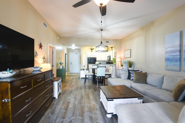 living room featuring wood-type flooring and ceiling fan with notable chandelier