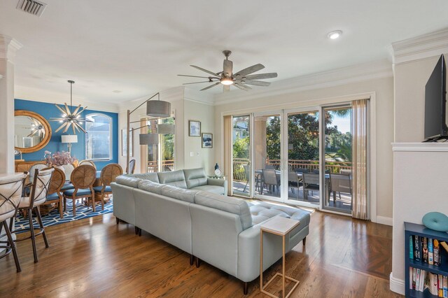 living room with crown molding, dark hardwood / wood-style floors, and ceiling fan with notable chandelier