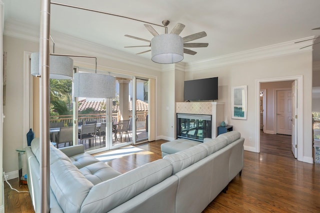 living room featuring a tile fireplace, crown molding, ceiling fan, and dark wood-type flooring