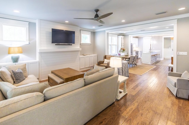 living room featuring hardwood / wood-style floors, ceiling fan, and ornamental molding