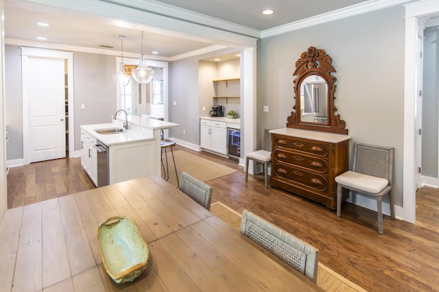 dining area with light hardwood / wood-style floors, ornamental molding, sink, and wine cooler