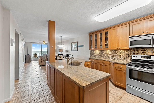 kitchen featuring light stone countertops, appliances with stainless steel finishes, tasteful backsplash, a textured ceiling, and sink