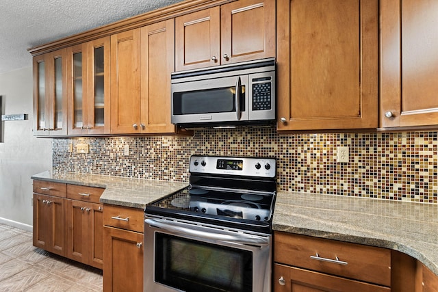 kitchen with decorative backsplash, light stone counters, and appliances with stainless steel finishes