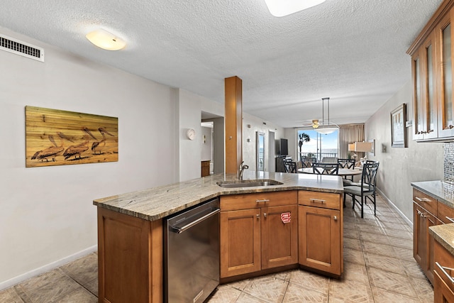 kitchen featuring stainless steel dishwasher, a textured ceiling, a kitchen island with sink, sink, and decorative light fixtures