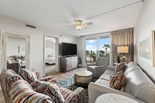 carpeted living room featuring ceiling fan and a textured ceiling