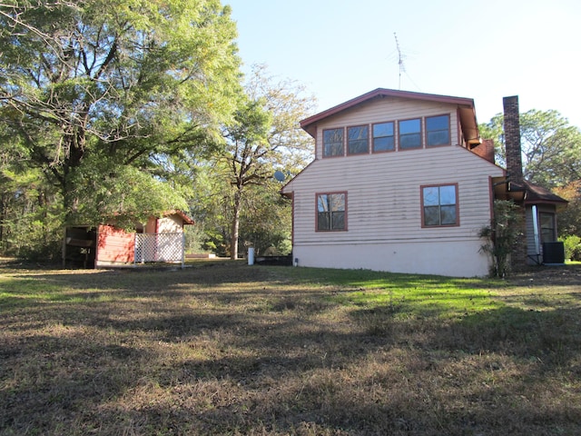 rear view of house featuring a lawn and central AC unit