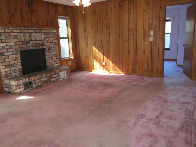 unfurnished living room with carpet flooring, a brick fireplace, and wood walls