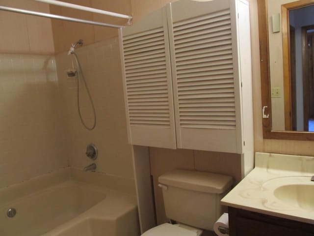 full bathroom featuring vanity, tiled shower / bath combo, and toilet