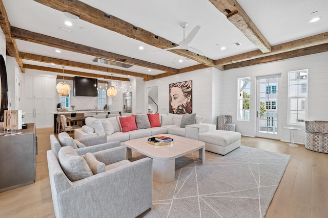 living room featuring ceiling fan, light hardwood / wood-style flooring, and beamed ceiling