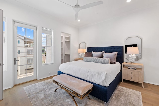 bedroom featuring a spacious closet, ceiling fan, light hardwood / wood-style flooring, a closet, and ornamental molding