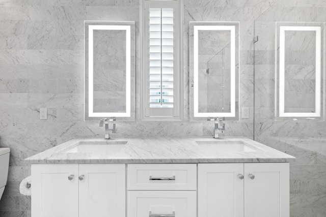 bathroom featuring vanity, toilet, and tile walls