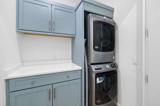 clothes washing area featuring cabinets and stacked washer and clothes dryer