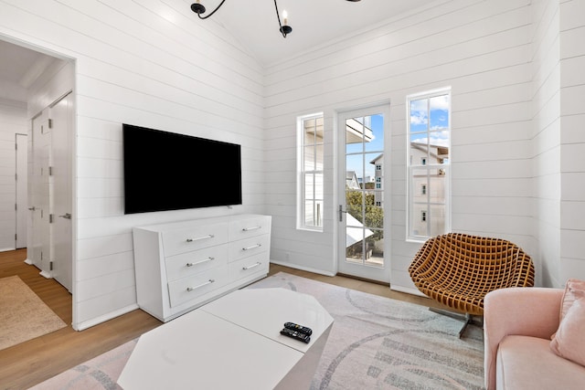 living room featuring light wood-type flooring, high vaulted ceiling, and wood walls