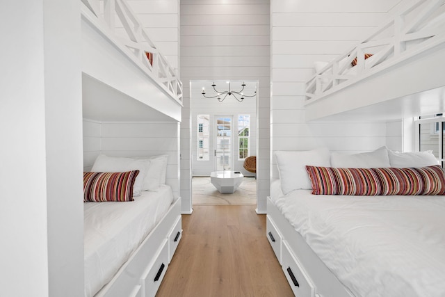 bedroom with wood walls and light hardwood / wood-style floors