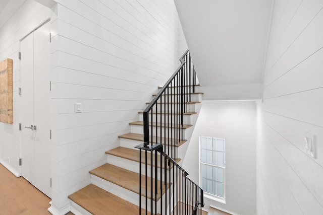 staircase with wood-type flooring and vaulted ceiling