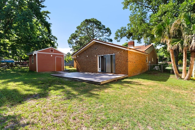 rear view of house with a yard, a deck, and a storage shed