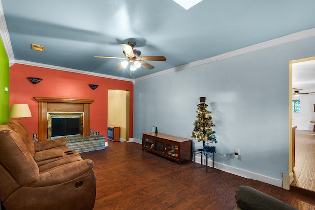 living room featuring dark hardwood / wood-style floors, ceiling fan, crown molding, and a brick fireplace