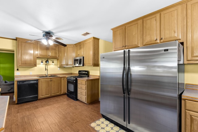 kitchen with black appliances, ceiling fan, light hardwood / wood-style floors, and sink