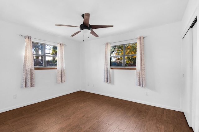 unfurnished room featuring plenty of natural light, dark wood-type flooring, and ceiling fan