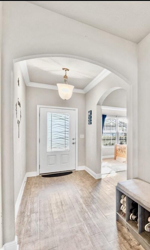 foyer with light wood-type flooring and crown molding